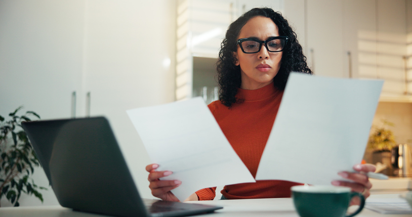 Woman, reading and paperwork with laptop at house for finance report, budget planning and payment. Female person, documents and pc for expenses, mortgage bills and invoice information of banking loan